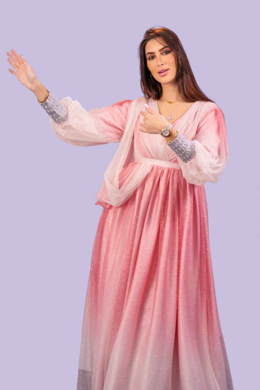 فستان من التور باللون الوردي، ببطانة لامعة، وصدرية مميزة، وأكمام مطرزة يدوياً